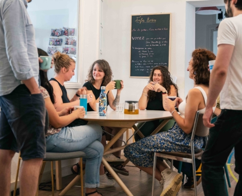 Photo d'un groupe de coworkers qui partagent un café avec le sourire. Moment convivial. Pièce lumineuse.