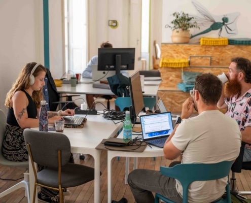 Photo d'un espace de travail ouvert et lumineux. Des personnes travaillent avec des écrans d'ordinateurs et boivent du café.